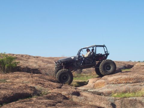 2004 Aston Martin Virage - A custom off-road buggy navigates a challenging rocky landscape under a clear blue sky.