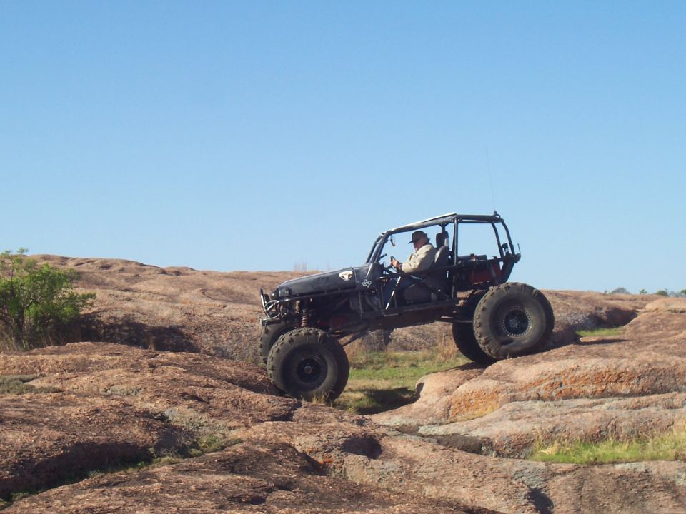 Off-road buggy with large tires climbing over rocks