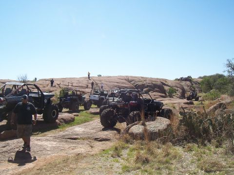 2004 Aston Martin Virage - A group of off-road vehicles navigate a challenging, rocky landscape under a bright, clear sky.