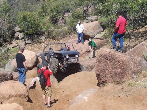 2004 Aston Martin Virage - An off-road buggy navigates a challenging rocky incline while spectators observe the action.