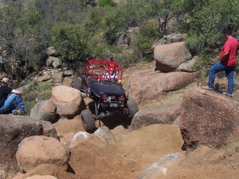 2004 Aston Martin Virage - A modified buggy tackles a challenging off-road course with spectators watching.