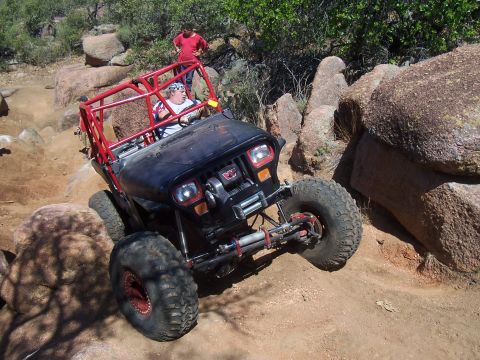 2004 Aston Martin Virage - An off-road vehicle navigates a rocky trail with a person standing in the background.