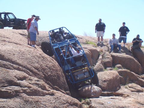 2004 Aston Martin Virage - An off-road buggy navigates a challenging rocky incline, with spectators observing the difficult climb.