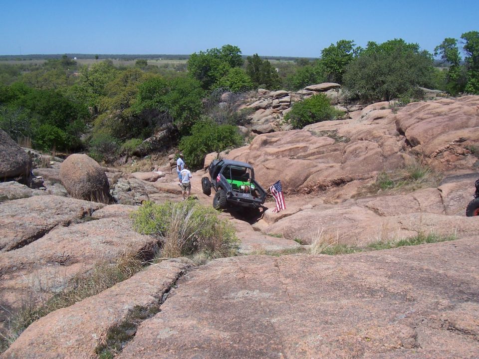 Off-road vehicle with American flag on rocky terrain