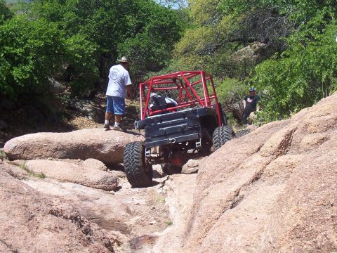 2004 Aston Martin Virage - An off-road buggy navigates a challenging rocky path with two people observing.