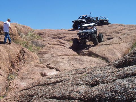2004 Aston Martin Virage - Off-road vehicles navigate a challenging rocky terrain on a sunny day.