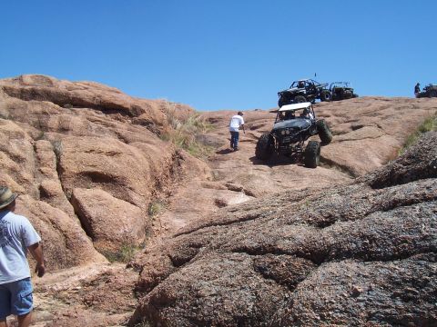 2004 Aston Martin Virage - Off-road vehicles navigate a challenging rocky terrain on a sunny day.