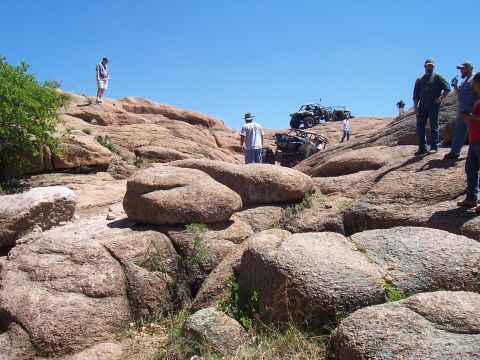 2004 Aston Martin Virage - Off-road vehicles navigate a challenging rocky landscape with spectators observing the action.