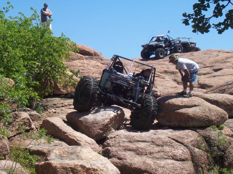 2004 Aston Martin Virage - Two off-road vehicles navigate a rocky terrain under a clear blue sky.