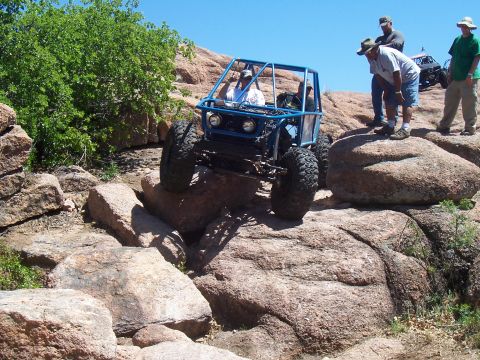 2004 Aston Martin Virage - An off-road buggy navigates a rocky terrain with spectators watching.