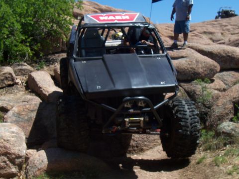 2004 Aston Martin Virage - Off-road buggy with WARN logo on roof, navigating rocky terrain. Another off-road vehicle visible in the background.