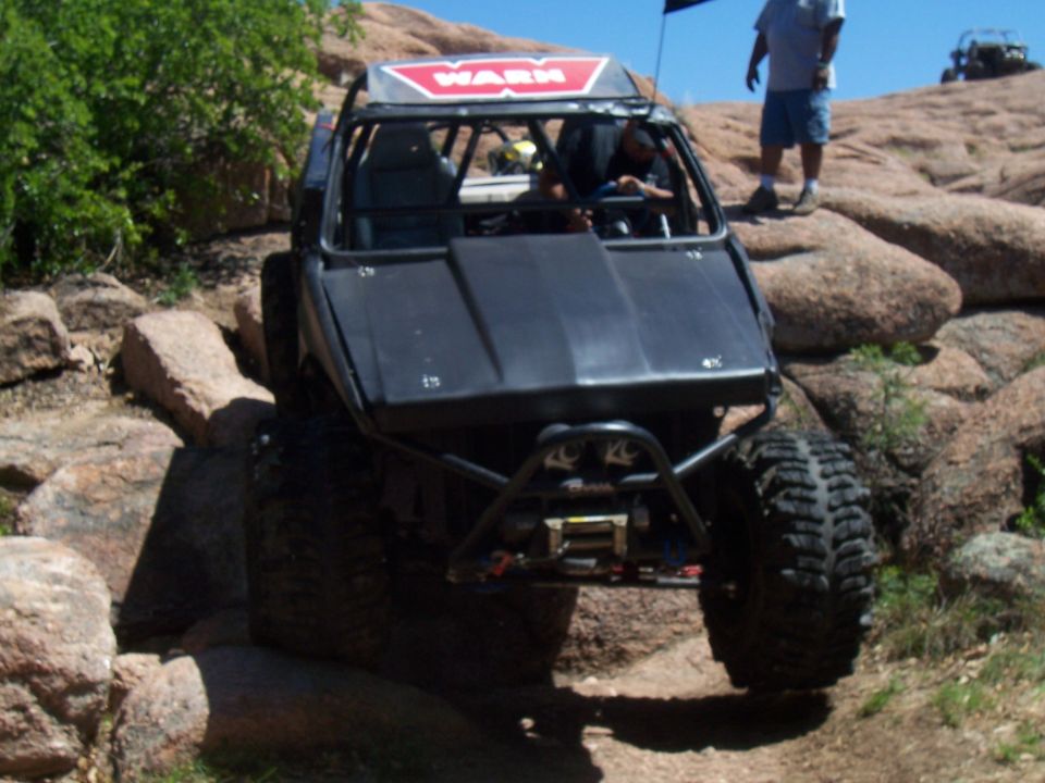 Off-road buggy with WARN logo on roof, navigating rocky terrain. Another off-road vehicle visible in the background