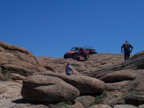2004 Aston Martin Virage - Off-road vehicles navigate a challenging rocky landscape under a bright blue sky.