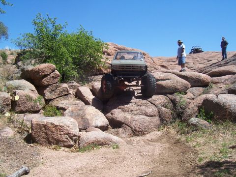 2004 Aston Martin Virage - Off-road vehicle navigating a challenging rocky terrain under a clear blue sky.