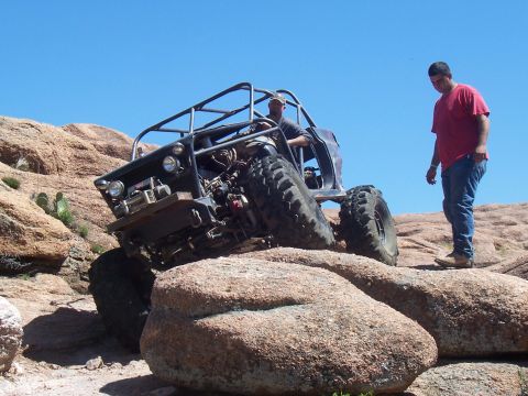 2004 Aston Martin Virage - Custom off-road buggy navigates challenging rocky terrain under a clear blue sky.