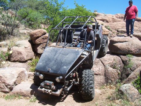 2004 Aston Martin Virage - Off-road buggy navigates a steep, rocky incline with a driver and passenger.