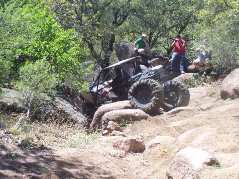 2004 Aston Martin Virage - An off-road buggy navigates a challenging rocky course, with spectators observing the action.