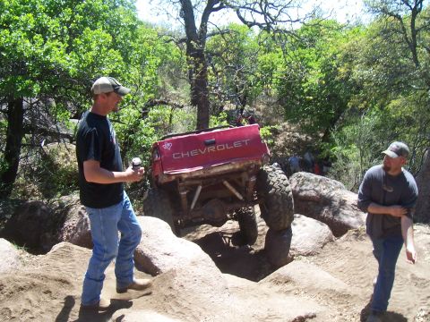 2004 Aston Martin Virage - A modified Chevrolet pickup truck is shown attempting to traverse a challenging off-road course with large rocks.