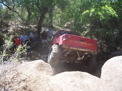 2004 Aston Martin Virage - A red Chevrolet pickup truck tackles a challenging off-road course with spectators watching from the side.