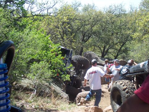 2004 Aston Martin Virage - An off-road vehicle is stuck on rocks during an outing, with onlookers observing the situation.