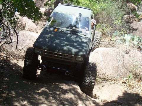 2004 Aston Martin Virage - A modified Toyota pickup truck tackles a challenging off-road course with large boulders and steep inclines.