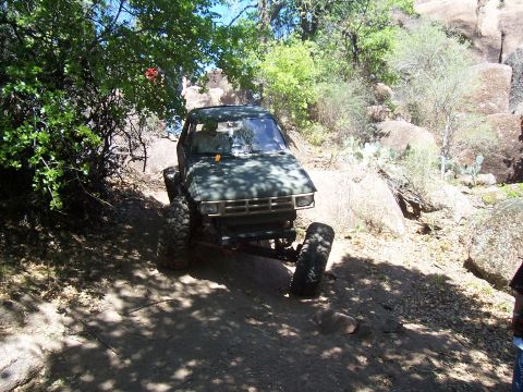 2004 Aston Martin Virage - A modified off-road truck navigates a rocky, wooded trail.