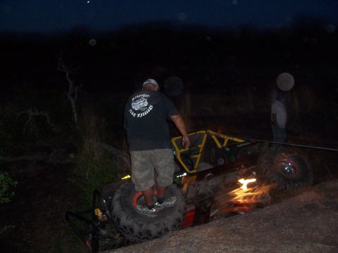 2004 Aston Martin Virage - An off-road buggy is seen tipped on its side in a rocky, outdoor environment at night.