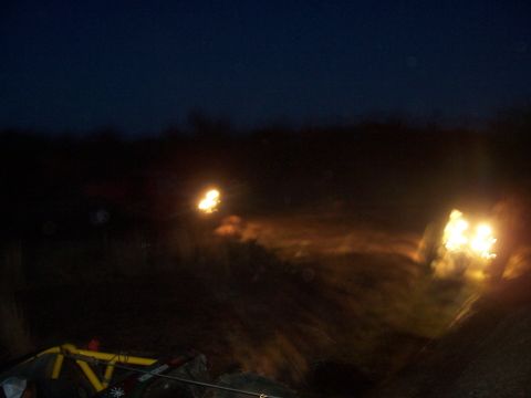 2004 Aston Martin Virage - Headlights pierce the darkness as off-road vehicles navigate a rough terrain at night.