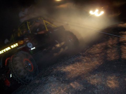2004 Aston Martin Virage - An off-road buggy, labeled "RIVER RAT", navigates a dusty and foggy terrain at night.