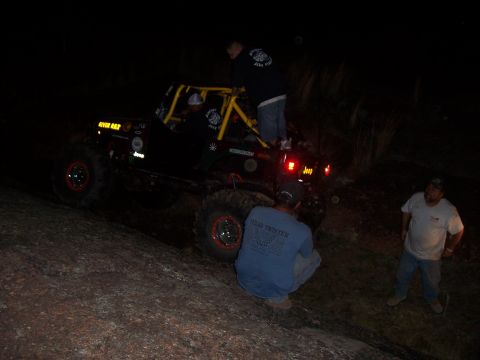 2004 Aston Martin Virage - A group of people are gathered around a modified Jeep during an off-road excursion at night.