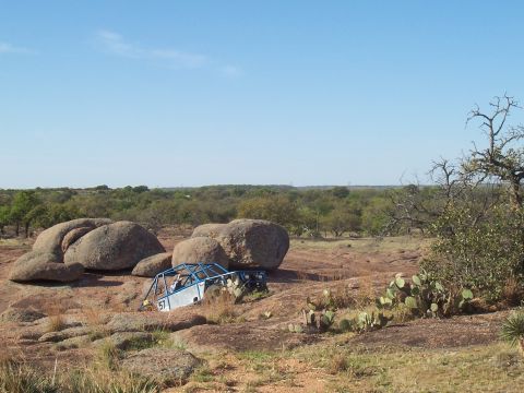 2004 Aston Martin Virage - A custom buggy navigates a rocky terrain, with one of its wheels stuck between boulders.