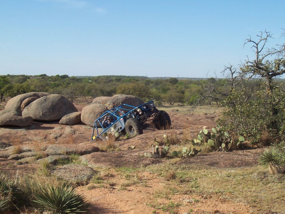 Blue off-road buggy with roll cage climbing rocky terrain