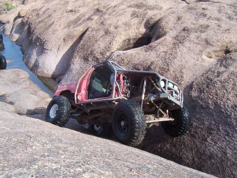 2004 Aston Martin Virage - This heavily modified buggy navigates a rocky terrain with a water feature nearby.