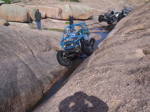 2004 Aston Martin Virage - Multiple off-road vehicles traverse a challenging rocky landscape with water channels.