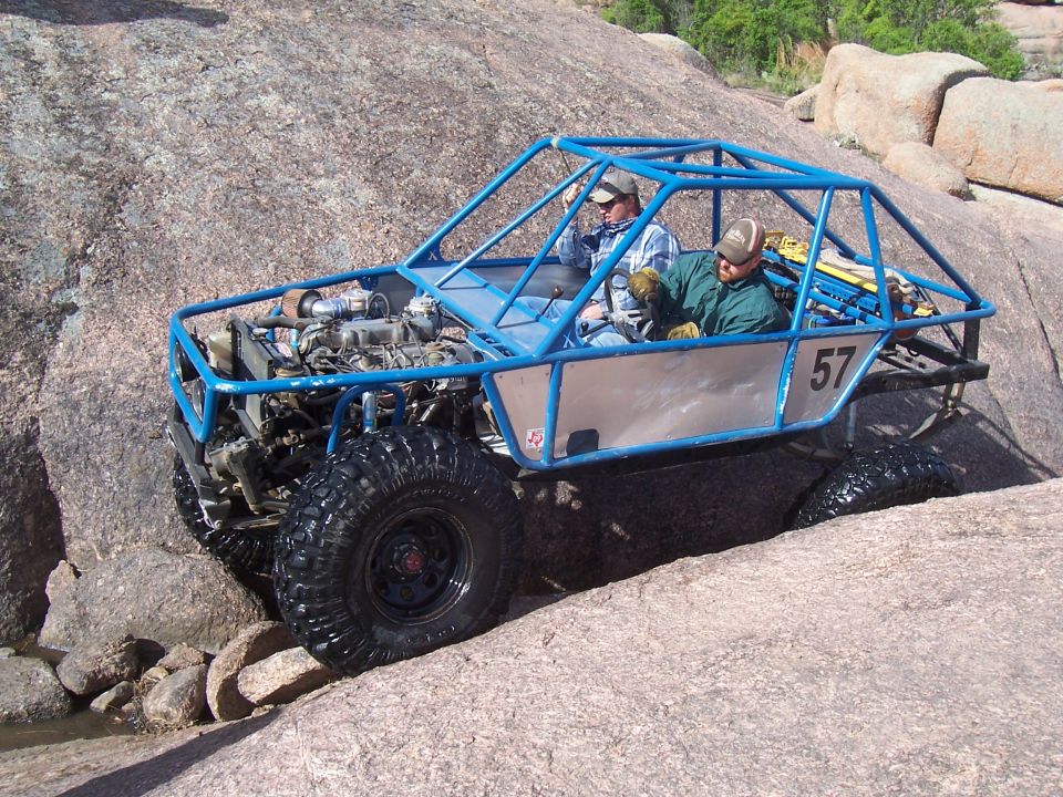 Blue tube-frame buggy number 57 with two occupants on boulders