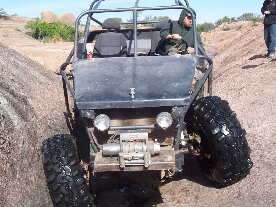 Front view of a black rock buggy with winch and driver on granite