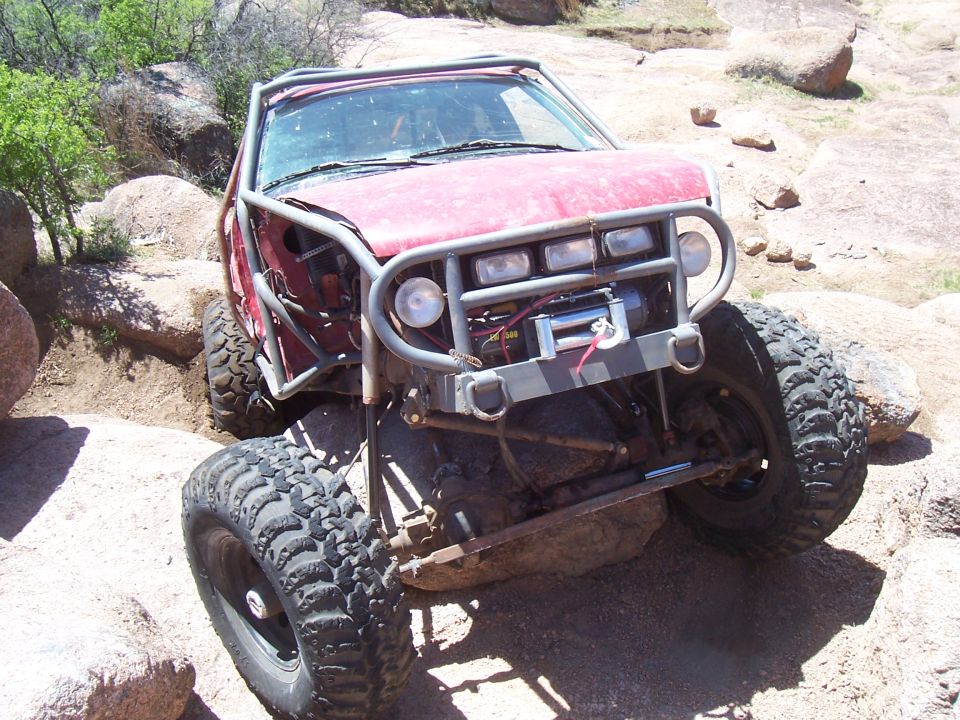 Front view of red off-road truck with winch on boulders