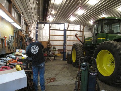 1992 Ford Bronco - Photograph of a farm workshop with a John Deere tractor and a vehicle lift, not a document.