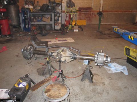 1992 Ford Bronco - Photograph of a full axle assembly supported on jack stands in a garage, not a document.