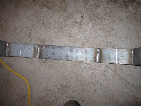 1992 Ford Bronco - Close-up photograph of a fabricated metal axle truss on a garage floor, not a document.