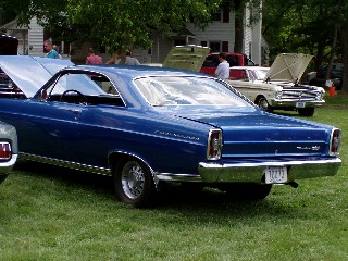 1999 Ford Crown Victoria - A blue classic car is shown from the rear, with another vehicle in the background.
