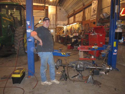 1992 Ford Bronco - Photograph of a person posing next to an axle assembly in a workshop, not a document.