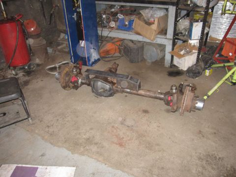 1992 Ford Bronco - Photograph of a removed vehicle front axle assembly on a garage floor, not a technical document.