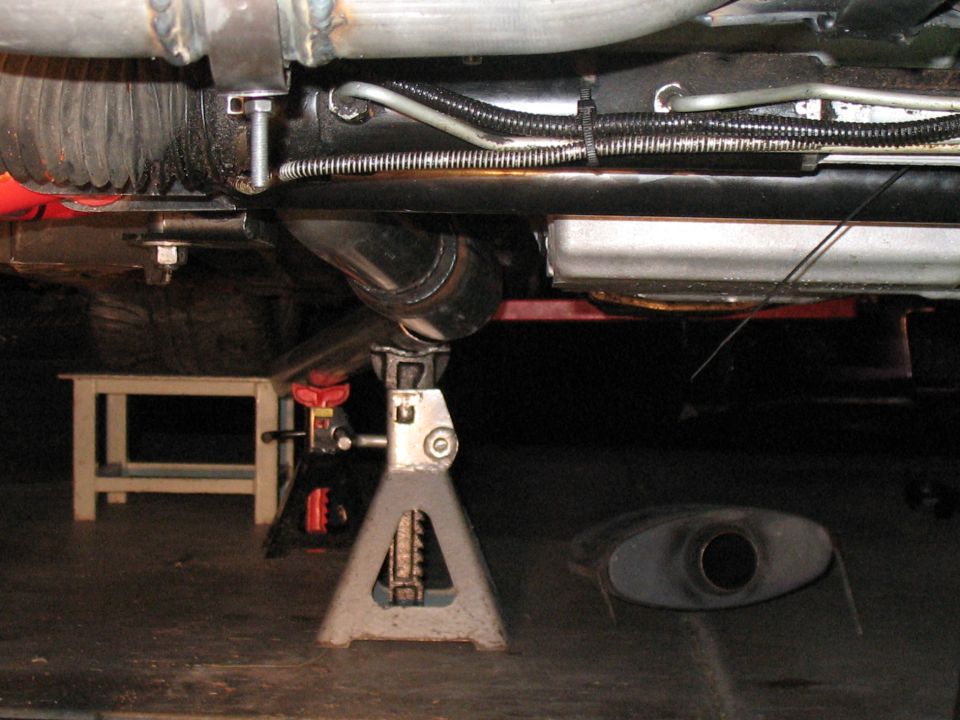 Underside of a vehicle on jack stands, showing exhaust and suspension parts.