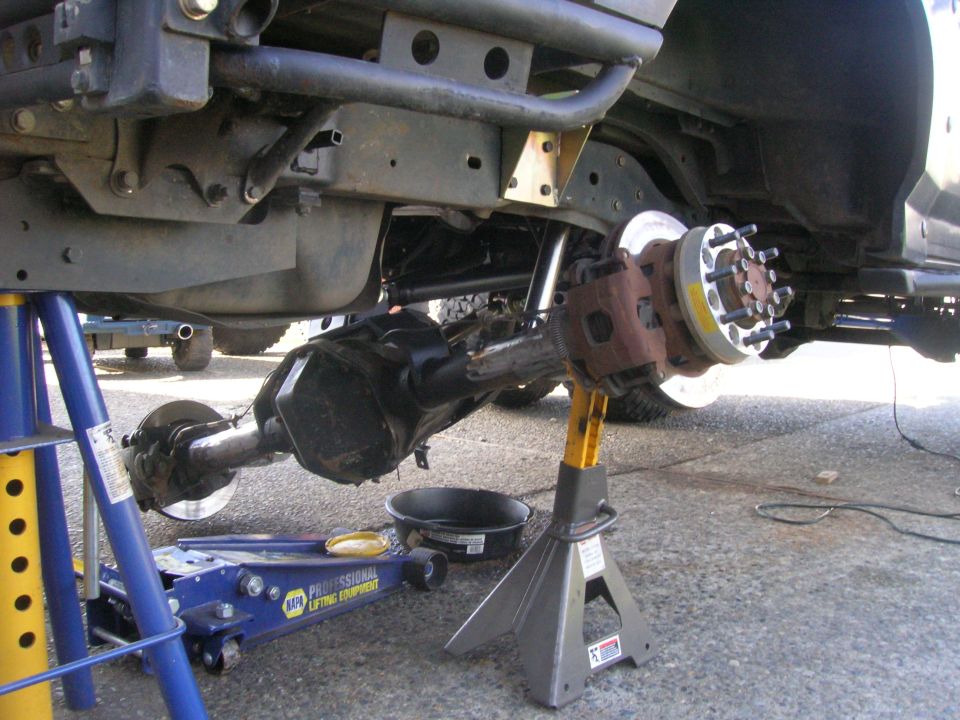 Underside of a vehicle with rear axle assembly and brake components on jack stands.