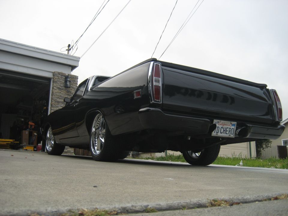 Black 1970 Ford Ranchero rear driver's side quarter view with chrome wheels and custom license plate.