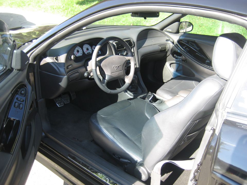 Interior of a black Ford Mustang, showing dashboard, steering wheel, and seats.