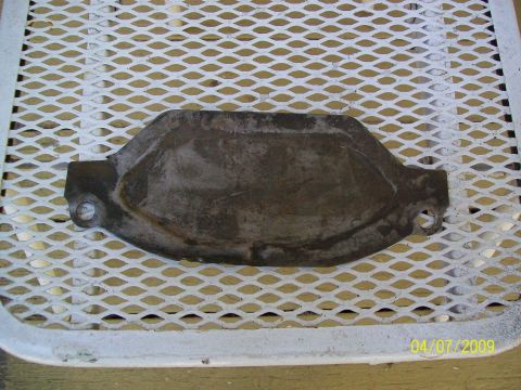 1972 Ford Ranchero - A rusty metal part, possibly a heat shield, is shown lying on a white expanded metal surface. The part has two circular holes, one on each…
