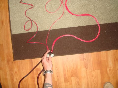 1992 Ford Bronco - A hand holds two electrical connectors connected to a bundle of red wires. The wires are spread out across a rug and wooden floor.