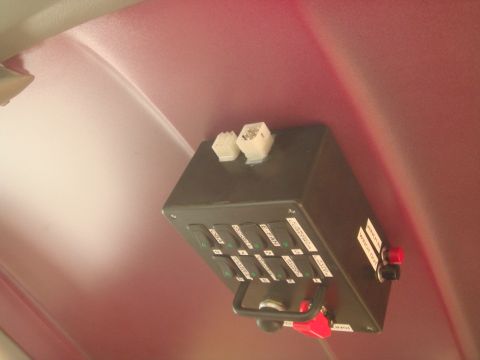1992 Ford Bronco - A custom-mounted switch panel with multiple labeled toggle switches and two red buttons is installed on the red interior headliner of a veh…